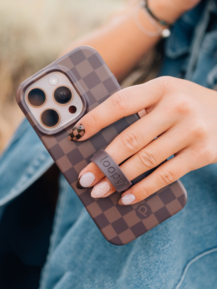 A woman holding a Cocoa Checkered Loopy Case. || feature-media