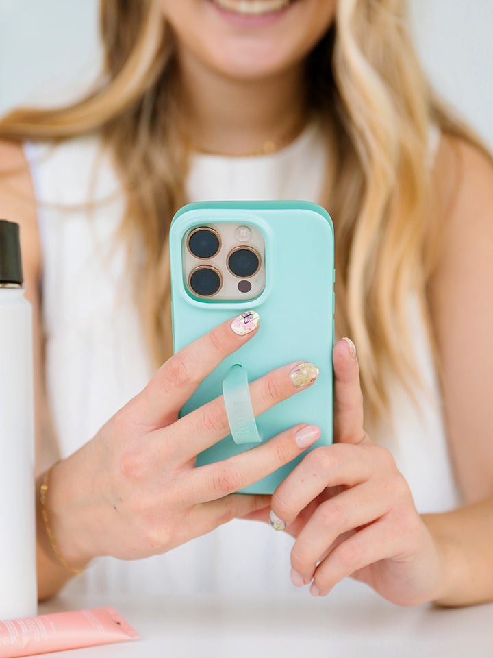 A woman holding a Mint Splash Loopy Case. || feature-media