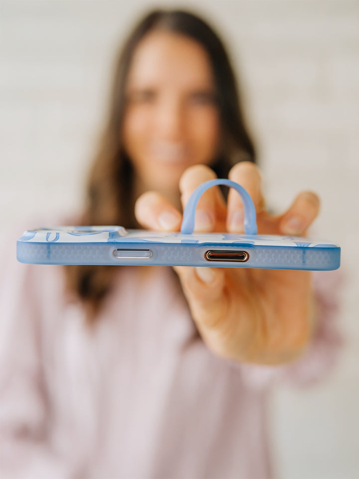 A woman holding a Blue Bows Loopy Case. || feature-media