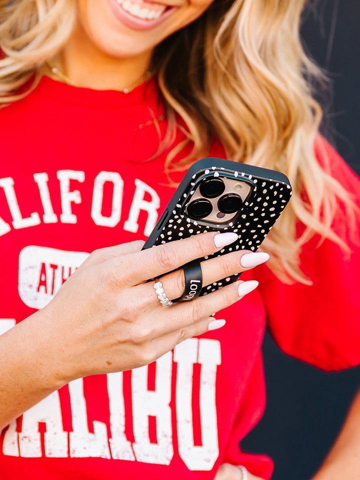 A woman holding a Noir Dots Loopy Case. || feature-media