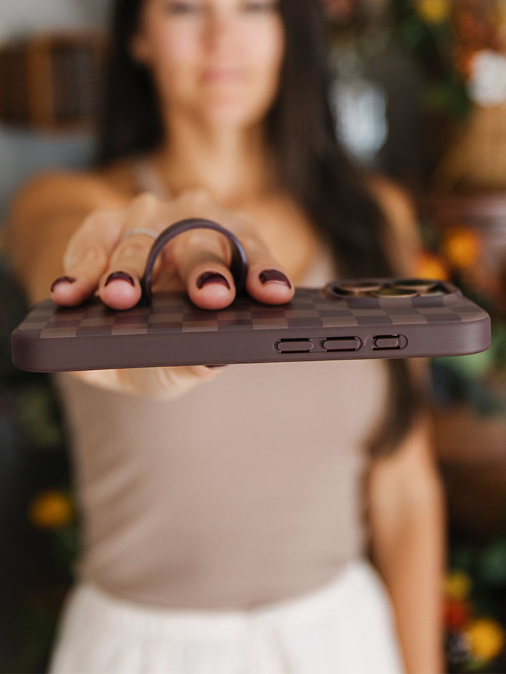 A woman holding a Cocoa Checkered Loopy Case. || feature-media