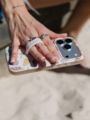A woman holding a Coastal Shells Loopy Case.|| feature-media