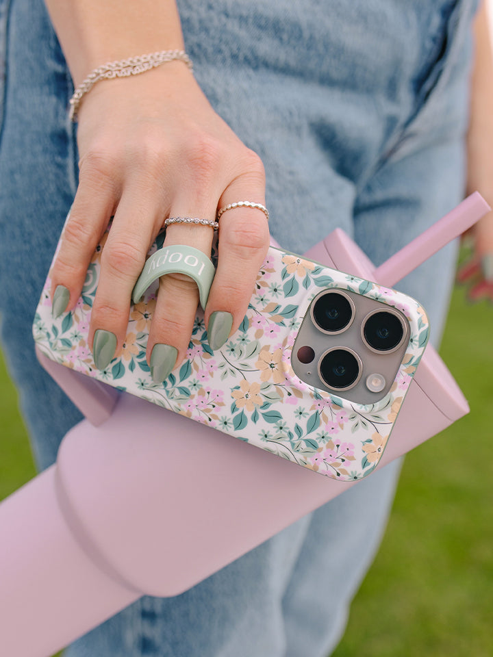 A woman holding an Apricot Blooms Loopy Case. || feature-media