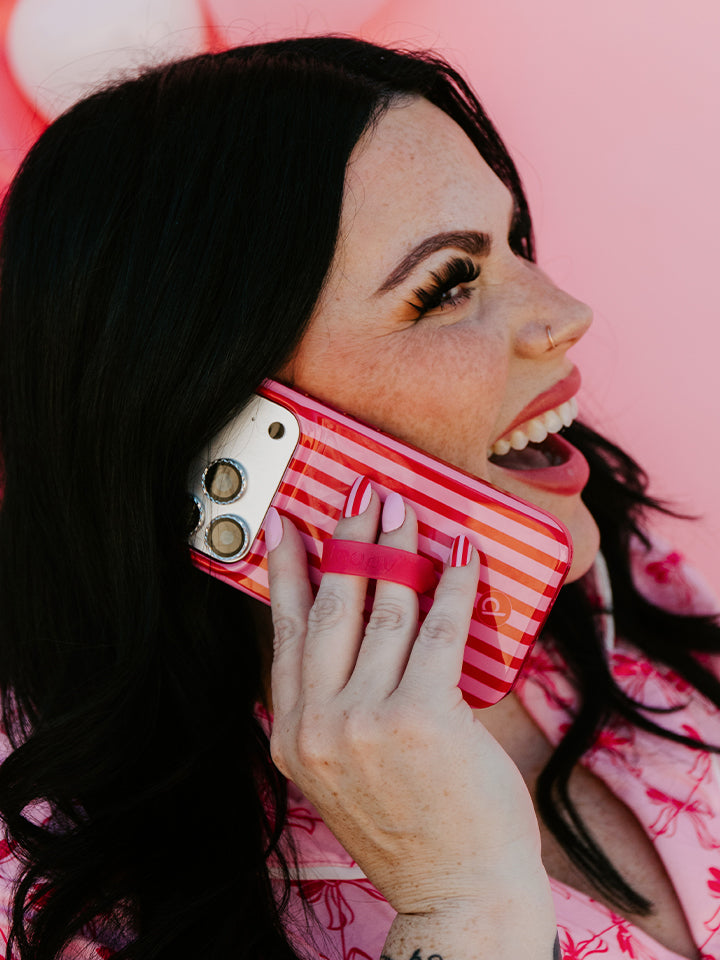 A woman talking on the phone while using a Berry Stripes Loopy Case. || feature-media