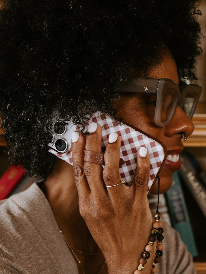 A woman holding a Brown Gingham Loopy Case. || feature-media