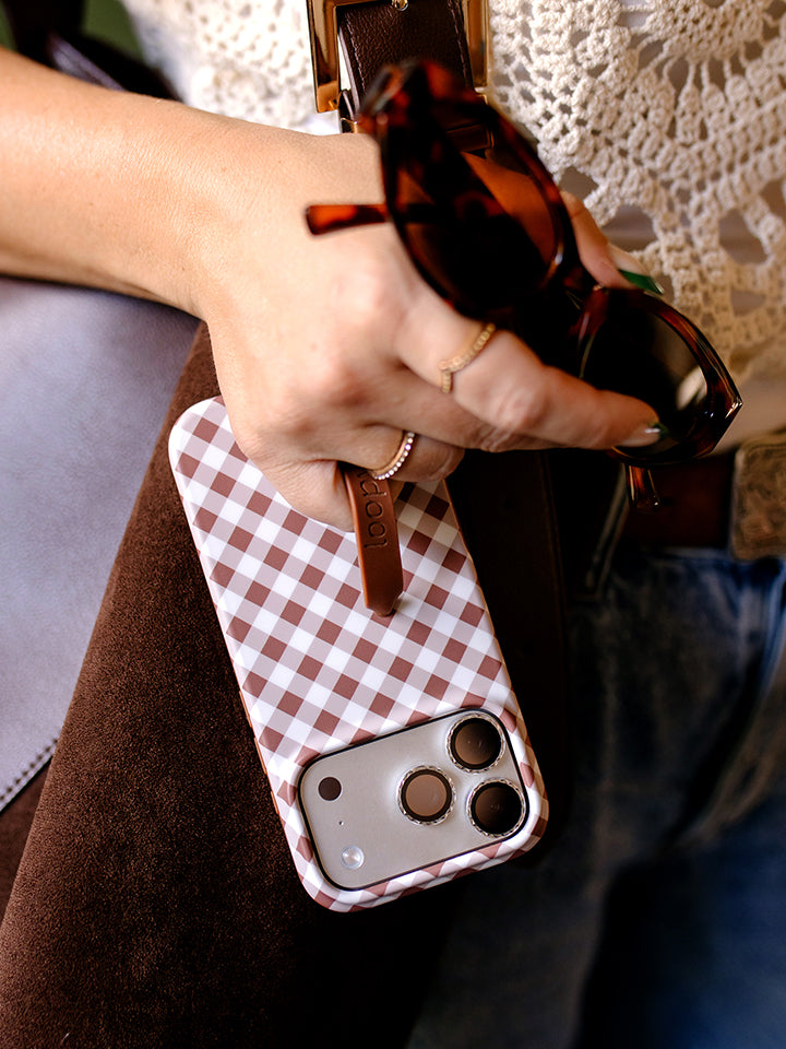 A woman holding a Brown Gingham Loopy Case. || feature-media