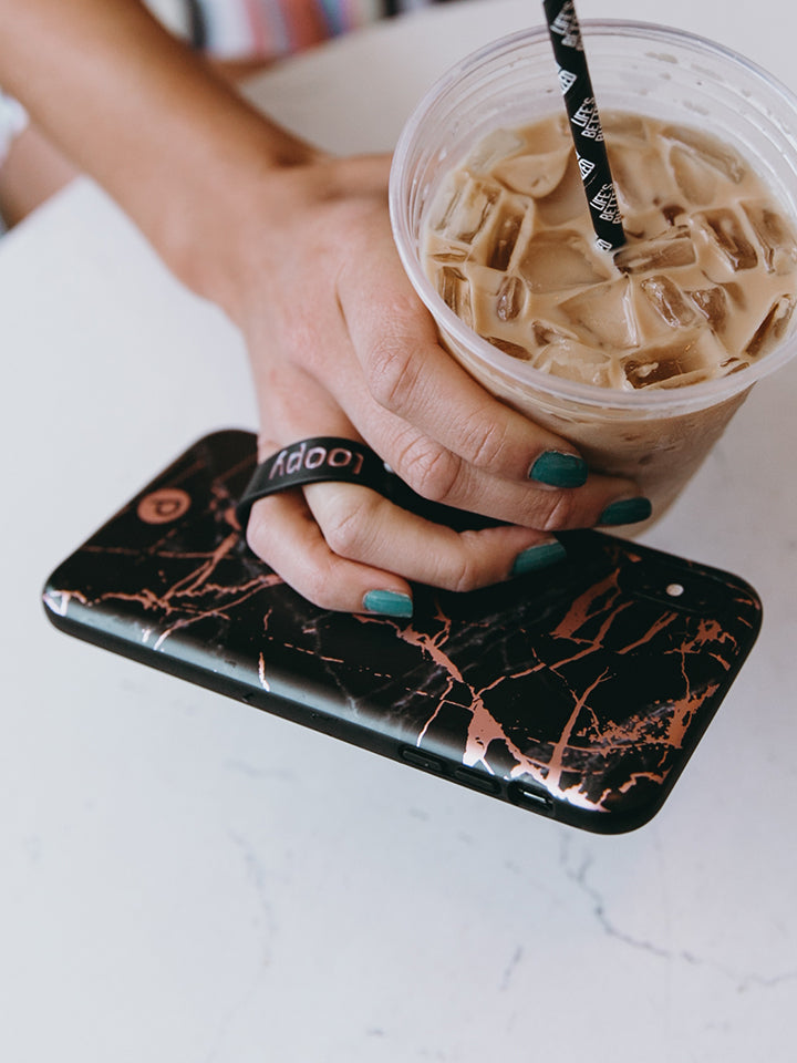 A woman holding a Black Rose Marble Metallic Loopy Case. 