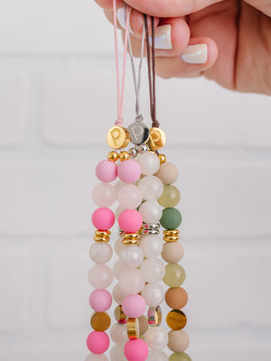 A woman holding a Posh Pink, White Aura, and Earthy Elegance Loopy Cases Wristlet.