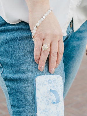 A woman wearing a White Aura Loopy Case Wristlet that is attached to a Blue Toile Loopy Case.