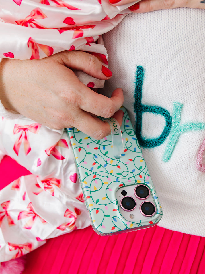 A woman holding a baby while holding a Merry and Bright Loopy Case. || feature-media