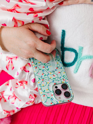 A woman holding a baby while holding a Merry and Bright Loopy Case. || feature-media