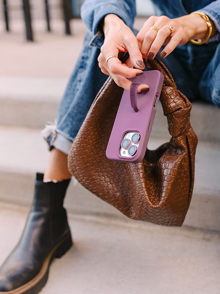 A woman holding a Dusty Plum Loopy Case. || feature-media