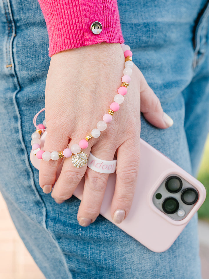 A woman wearing a Posh Pink Loopy Cases Wristlet that is attached to a Blush Loopy Case.