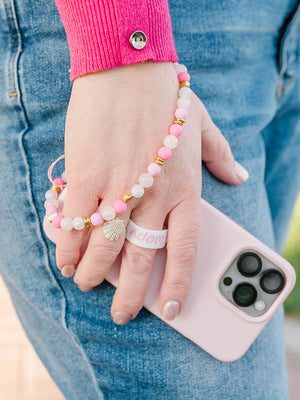 A woman wearing a Posh Pink Loopy Cases Wristlet that is attached to a Blush Loopy Case.