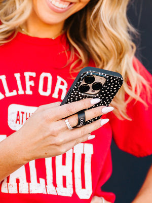 A woman holding a Noir Dots Loopy Case. || feature-media