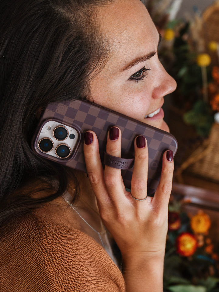 A woman holding a Cocoa Checkered Loopy Case. || feature-media
