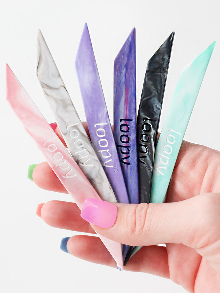 A woman holding six Loopy Cases Marble Super Loops.