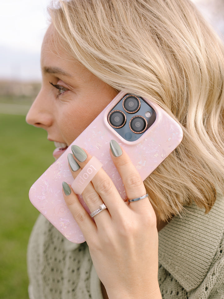 A woman talking on the phone while using a Blush Moonstone Loopy Case. || feature-media
