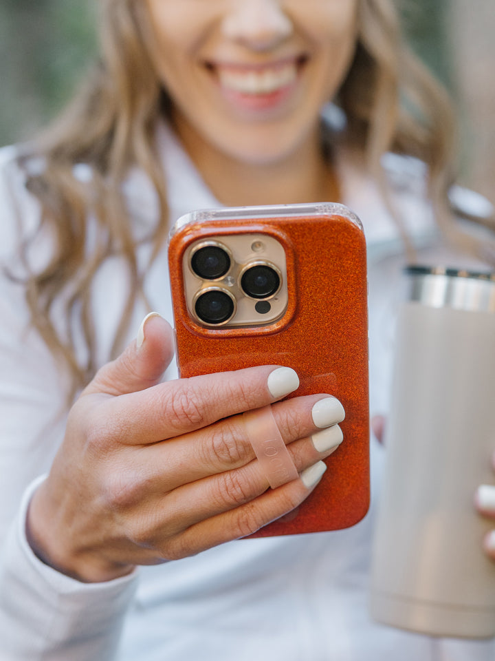 A woman holding an Orange Shimmer Loopy Case. || feature-media
