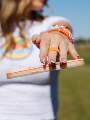 A woman holding a Peach Fizz Loopy Case. || feature-media