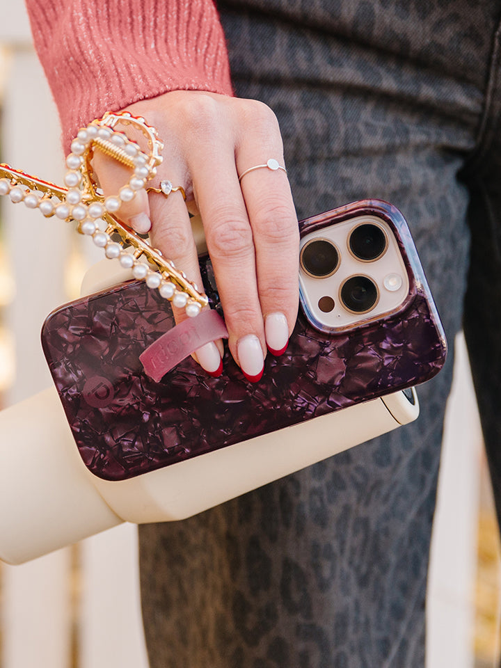 A woman holding a Wine Opal Shell Loopy Case. || feature-media